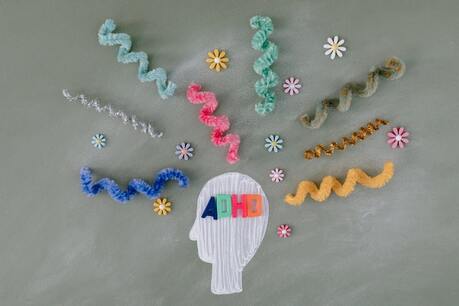 head silhouette with ADHD written on it and multicolor flowers and twines imitating hair 