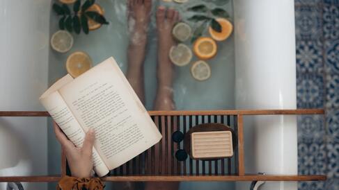 A woman mastering the art of balance and taking a relaxing bath while reading a book.