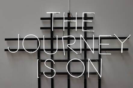 the journey is on a neon sign in B&W 