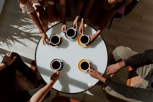 Multiple people holding cups of coffee.
