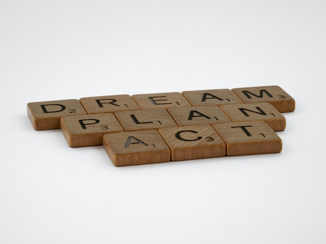 Pieces of Scrabble forming the words: dream, plan, act.