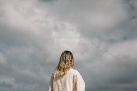 Woman looking at a cloudy, gray sky.